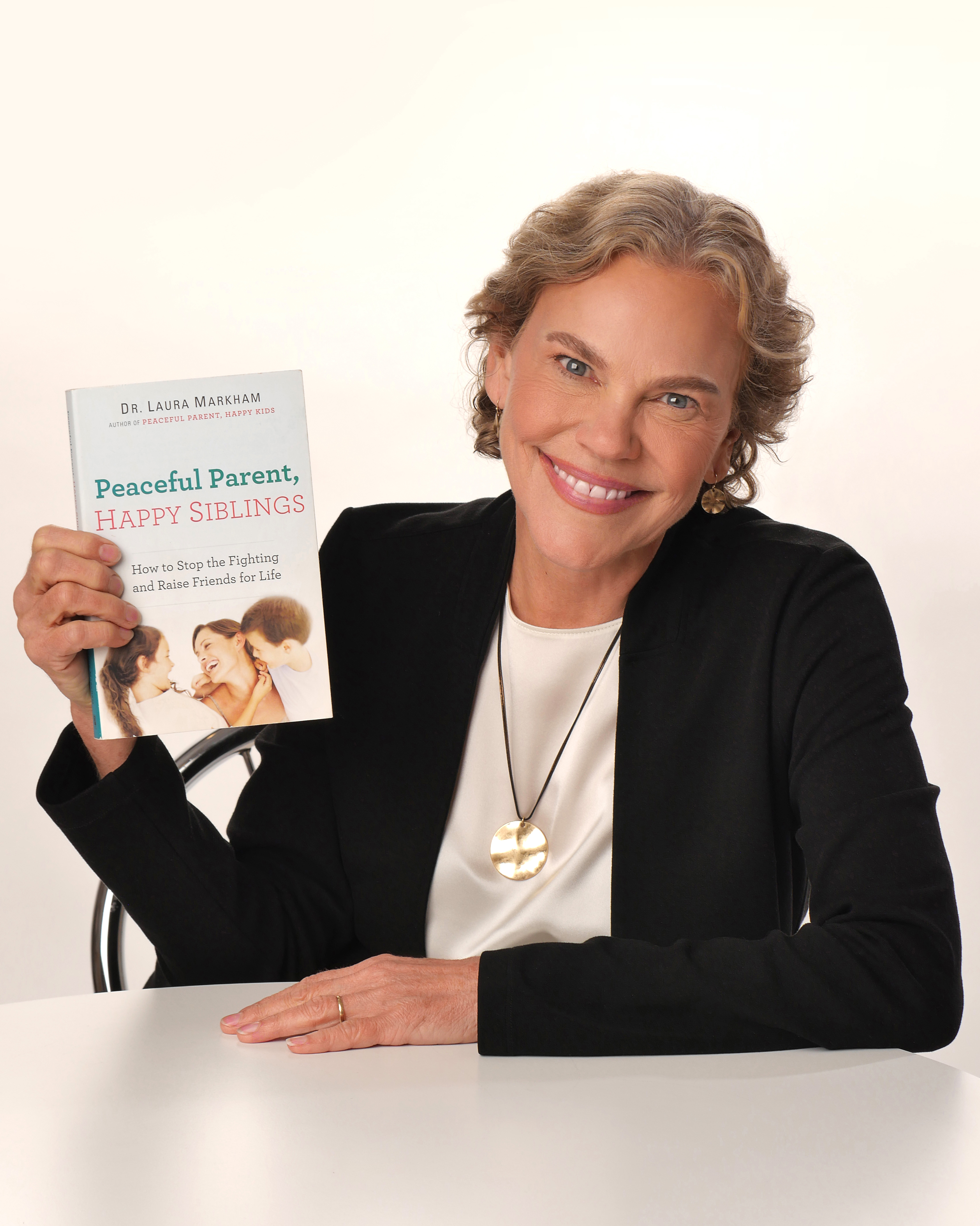 Dr. Laura Markham holding her book Peaceful Parent, Happy Siblings